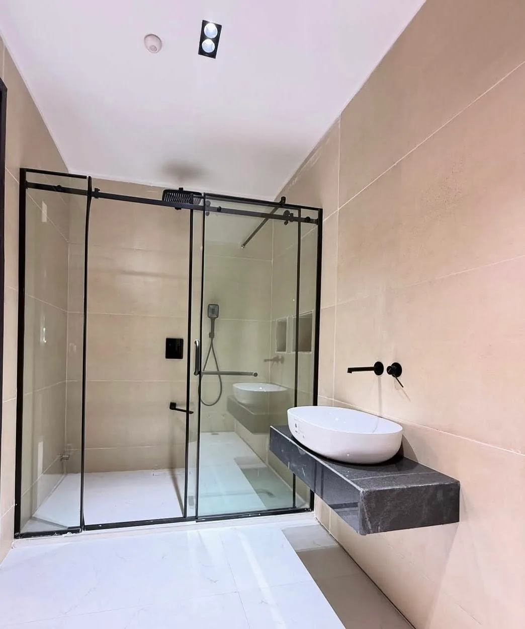 Minimalist bathroom with black-framed glass shower enclosure and floating dark marble sink console