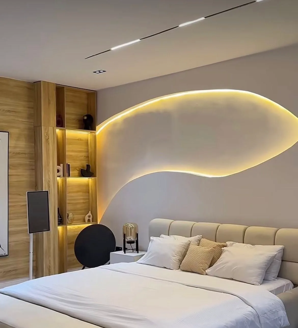 Bedroom with organic wave-shaped LED headboard, wood panel shelving with warm backlighting, and linear ceiling track light