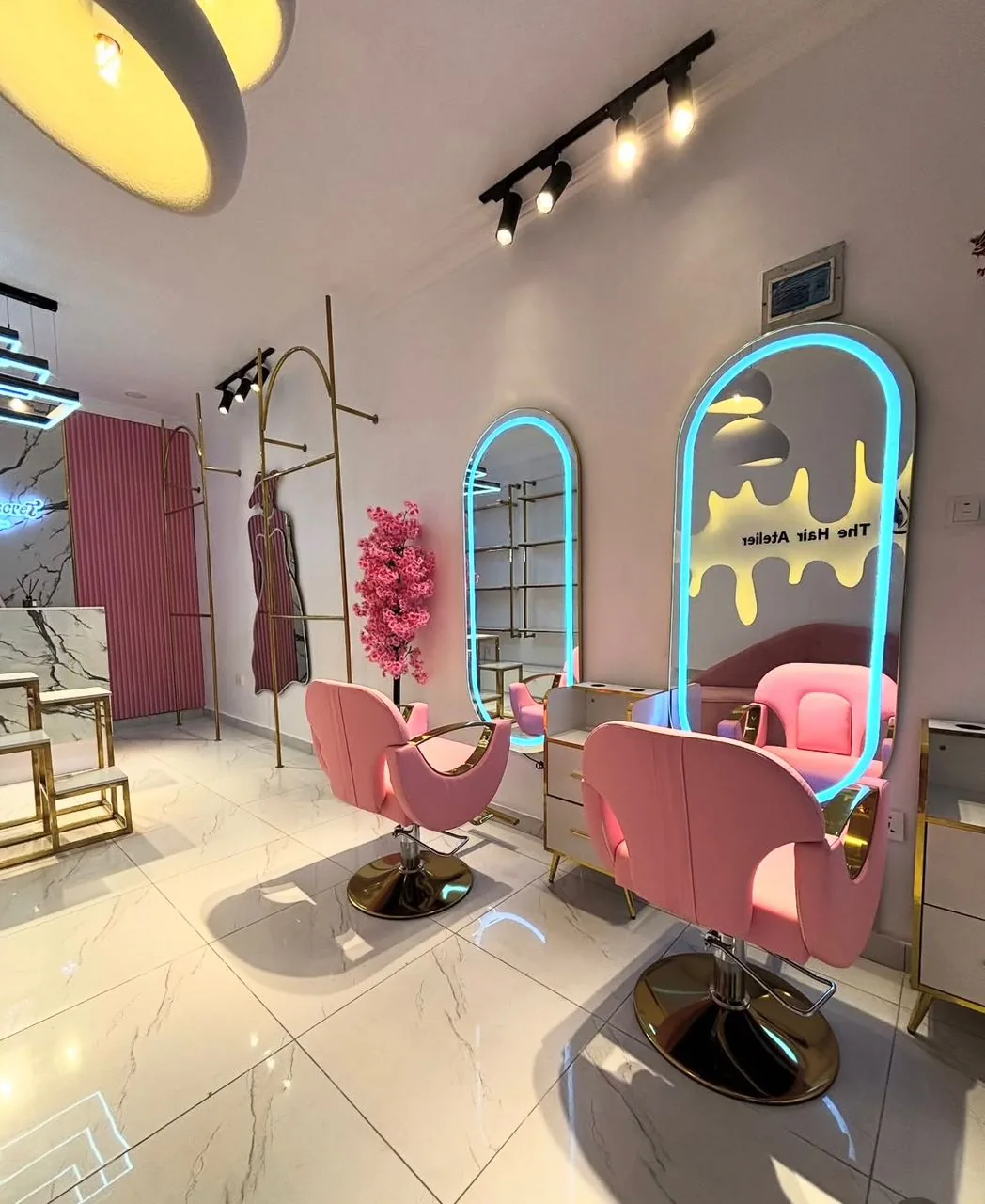 Styling stations with pink chairs and blue neon-backlit arched mirrors